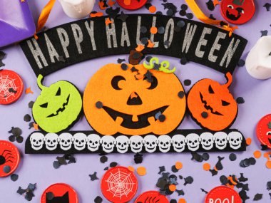 Happy halloween greetings decor with pumpkins on purple background with orange decor