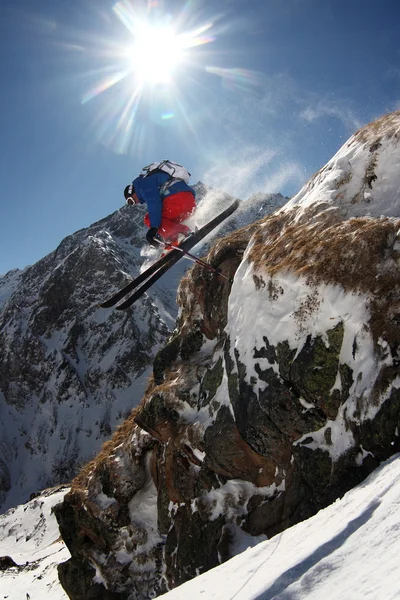 Skiër springen tegen blauwe hemel van de rots in zonnige dag — Stockfoto