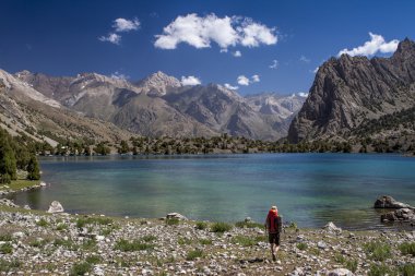 Backpacker dağ gölü nün su turkuaz yürümek.