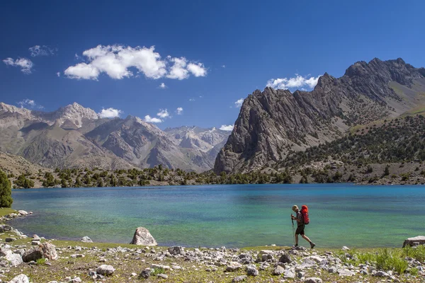 Backpacker a piedi lungo l'acqua turchese del lago di montagna . — Foto Stock