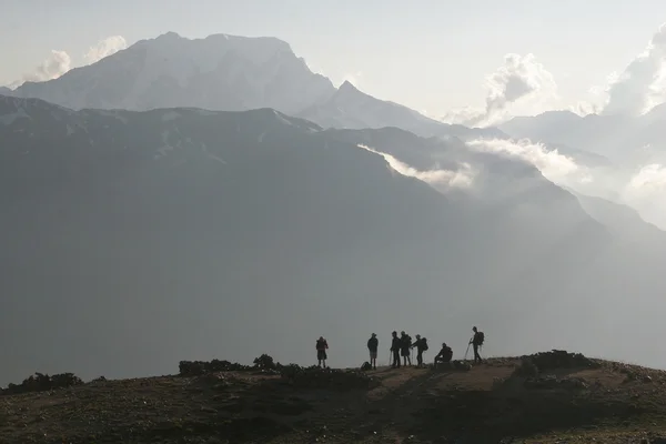 Trekking grubu günbatımı zamanı içinde bir dinlenme bir dağ geçidi vardır.