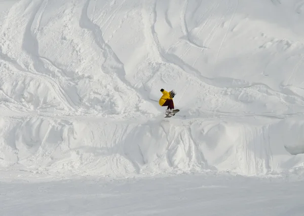 Hoppet av snowboardåkare på nedstigningen från mountain — Stockfoto