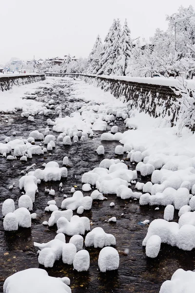 Bouchons de neige sur les rochers dans la rivière de montagne — Photo