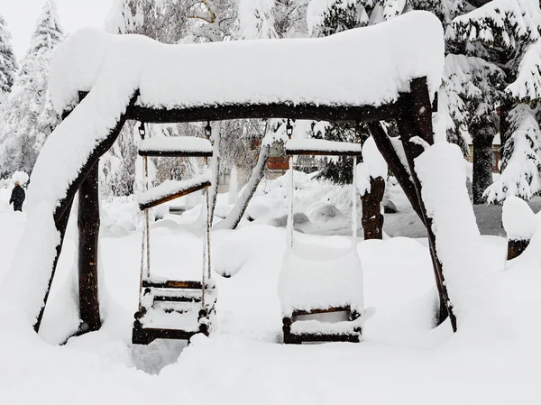 Dřevěná dětská houpačka krytá sněhem — Stock fotografie