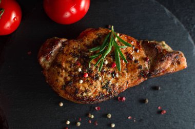 Siyah arka planda baharat ve domates serpiştirilmiş biftek. Hayat devam ediyor, yakın plan.