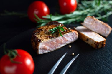 Siyah arka planda baharat ve domates serpiştirilmiş biftek. Hayat devam ediyor, yakın plan.