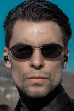 Pürüzsüz saç kesimi ve koyu güneş gözlüklü bir adamın portresi. Matrix filmindeki gizli ajan ya da karakter gibi görünüyor.