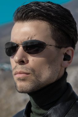 Pürüzsüz saç kesimi ve koyu güneş gözlüklü bir adamın portresi. Matrix filmindeki gizli ajan ya da karakter gibi görünüyor.