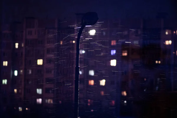 View from the window at night, light in the windows of apartments, a burning lantern, wet snow