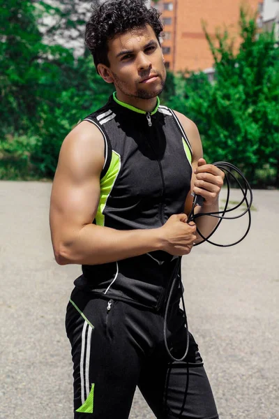 A man in a sport suit, with a skipping rope in his hands