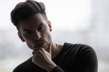Adamın eli çenesinde, düşünceli bir duruş ve kurnaz gözlerle.