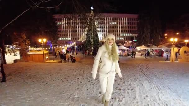 Pyatigorsk, Russia. 12/26/2020 A young girl walks on the main square of the city of Pyatigorsk, near the New Year tree around shops with snacks and souvenirs — Stock Video