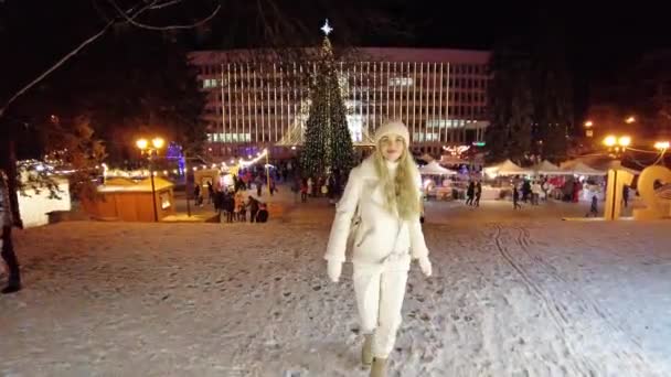 Pyatigorsk, Rusland. 26 / 12 / 2020 En ung pige går på hovedtorvet i byen Pyatigorsk, nær nytårstræet omkring butikker med snacks og souvenirs – Stock-video