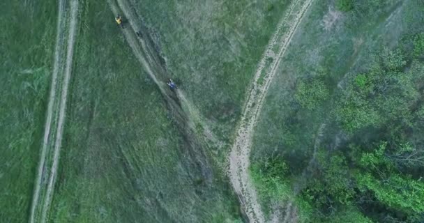 O quadricóptero voa em uma estrada rural perto da floresta ao longo da qual uma família anda de bicicleta — Vídeo de Stock