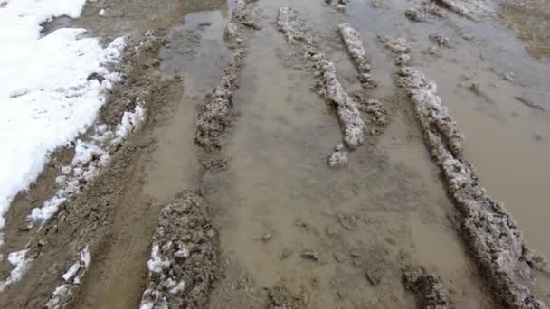 Una grande pozzanghera con neve sciolta sporca e una pista dalle ruote delle gomme dell'auto — Video Stock