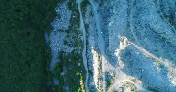 Egy drón repülése a sziklák felett a hegy lábánál, a kamera körbe forog, és egy napos nyári napon forog napnyugtakor. — Stock videók