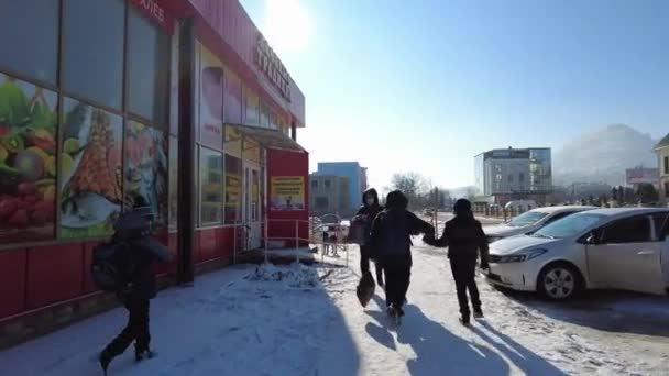 Moskva, Russland 01.15.2021 En gruppe skolebarn av elementære karakterer dropper leksjonene sine på en solrik vinterdag rotende rundt i gatene – stockvideo