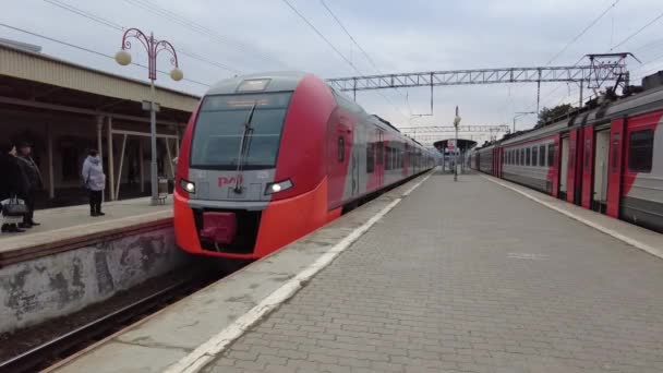 Essentuki, Ryssland. 02.13.2021 Järnvägsstationen i en liten semesterort, där passagerarna väntar på tåget på plattformen och där ett lok med vagnar närmar sig — Stockvideo