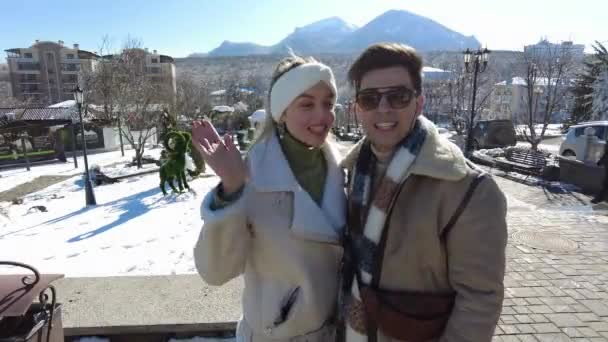 一对恋爱中的年轻夫妇，一个女孩和一个男人在冬日美景的背景下接吻，在远处，你可以看到雪峰覆盖的群山 — 图库视频影像
