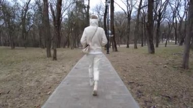 Kız arkasını döndü ve soğuk mevsimde ağaçlar boyunca park yolunda yürüdü.