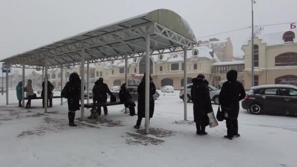 Mineralnye Vody, Russland. 03.12.2021. Passagiere stehen im Schneesturm an einer Bushaltestelle und warten auf ihren Bus im Winter — Stockvideo