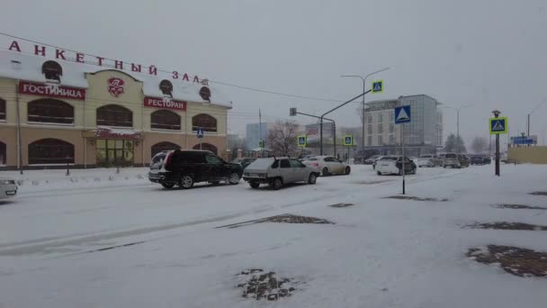 Mineralnye Vody, Oroszország. 2021. december 3. Az autók télen lassan haladnak a havas úton, míg az utasok a buszmegállóban várják a buszukat. — Stock videók