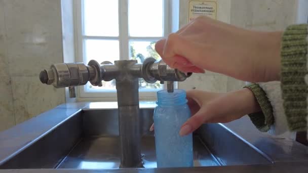 Menina coleta água mineral em uma galeria de bebidas em uma caneca e gosta de água potável — Vídeo de Stock