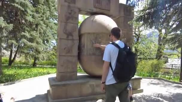 Zheleznovodsk, Territorium Stawropol, Russland 02.05.2021 Im Kurpark steht eine Skulptur der Tierkreiszeichen, zwei Männer versuchen, sie zu verdrehen, andere schauen zu. — Stockvideo
