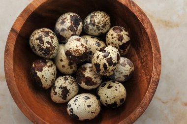 Mermer bir arka plan üzerinde ahşap bir kapta bıldırcın yumurta, üst görünümü