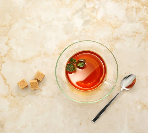 Τσάι σε μια διάφανη γυάλινη κούπα με πιατάκι σε μαρμάρινο φόντο. — Φωτογραφία Αρχείου