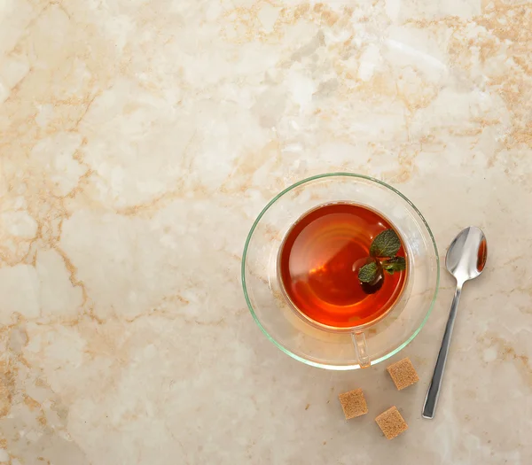 Τσάι σε μια διάφανη γυάλινη κούπα με πιατάκι σε μαρμάρινο φόντο. — Φωτογραφία Αρχείου