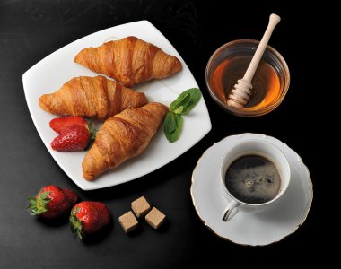 morning Breakfast - croissants with coffee and honey on black ba