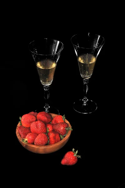 Bord met aardbeien en twee glazen met champagne op zwart — Stockfoto