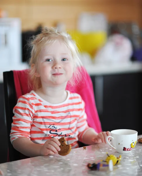 Linda niña con ojos azules bebe té con galletas — Foto de Stock