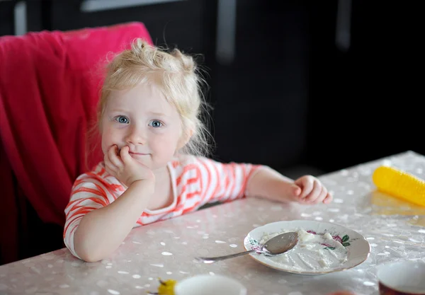 Cute little girl with blue eyes sitting after eating. empty plat — Stock Photo, Image