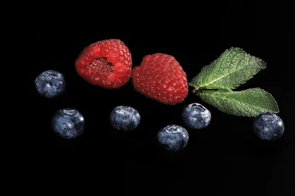 Raspberry dan blueberry dengan daun mint di backgrou hitam — Stok Foto