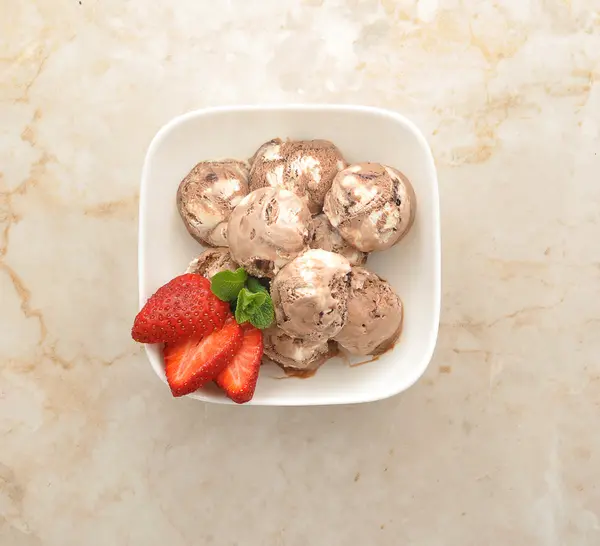 Шарики шоколадного мороженого с клубникой в белой тарелке — стоковое фото