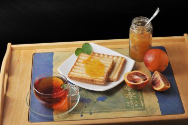 bread toast with orange marmalade. black mint tea in a transpare