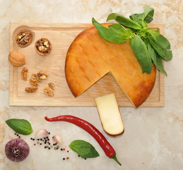 Cabeza de queso Suluguni ahumado sobre tabla de madera con nueces y —  Fotos de Stock