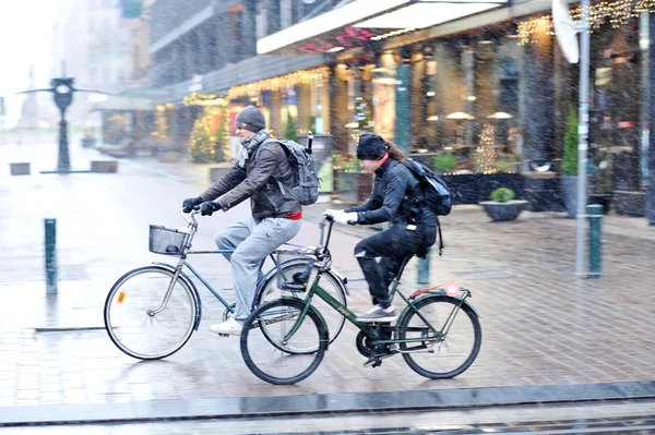 Pareja joven monta una bicicleta en mal tiempo con nieve —  Fotos de Stock