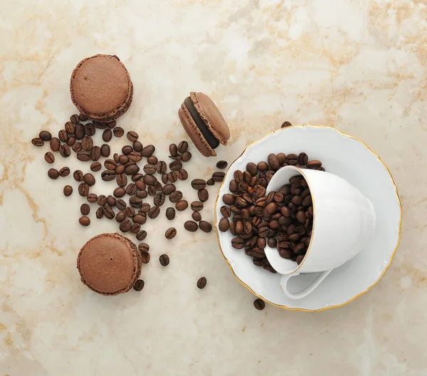 Чашка с кофейными зёрнами и шоколадными пирожными — стоковое фото