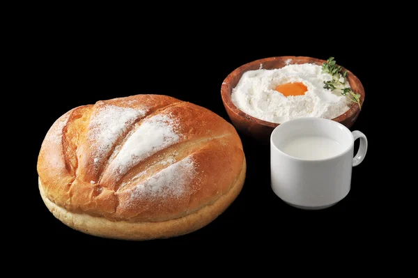 Round loaf of bread, milk in a Cup and the flour — Stock Photo, Image