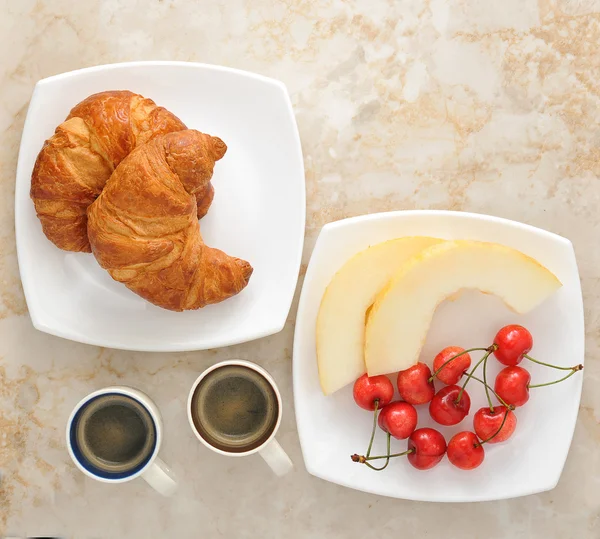 Petit déjeuner avec café, croissants et fruits - melon, cerises — Photo