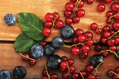 ahşap arka plan üzerinde meyveleri. Kırmızı kuş üzümü ve yaban mersini. 