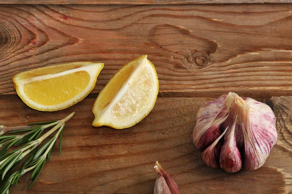 Λεμόνι, σκόρδο και δεντρολίβανο σε ένα ξύλινο υπόβαθρο σε ρουστίκ στυλ — Φωτογραφία Αρχείου