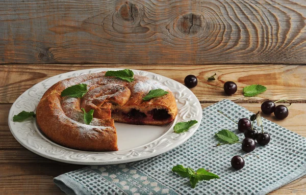 Strudel con ciliegie su piatto su fondo di legno — Foto Stock