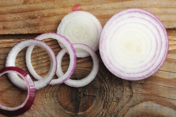 Rote Zwiebeln in Scheiben geschnitten auf einem hölzernen Hintergrund — Stockfoto