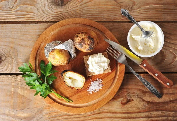 Aardappelen gebakken in folie op een houten achtergrond — Stockfoto