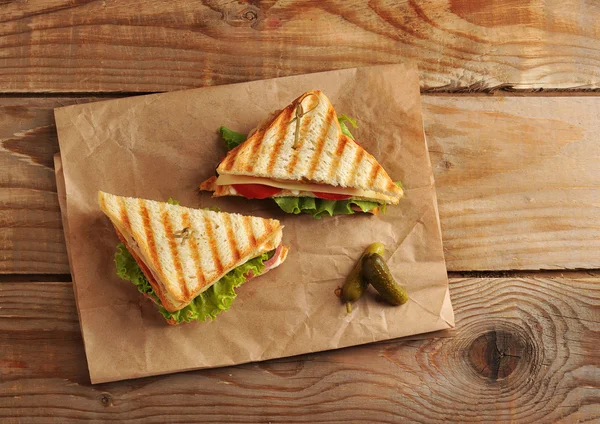 Dos encurtidos sándwich en una toalla de papel sobre fondo de madera — Foto de Stock