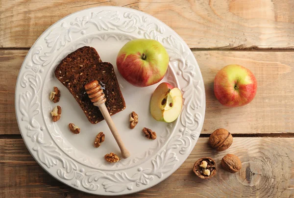 Colher de mel com pão, maçãs, nozes em um prato — Fotografia de Stock